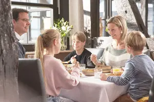Eine fünfköpfige Familie sitz am reichlich und frisch gedeckten Frühstückstisch.