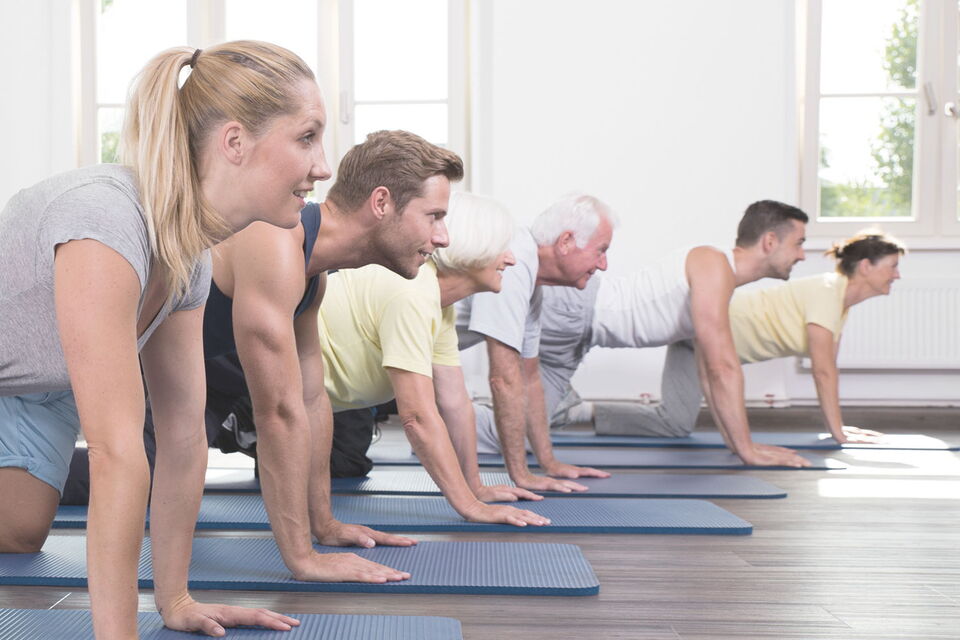 Gäste bei einer Fitnessübung auf der Matte im Sporthotel Grafenwald