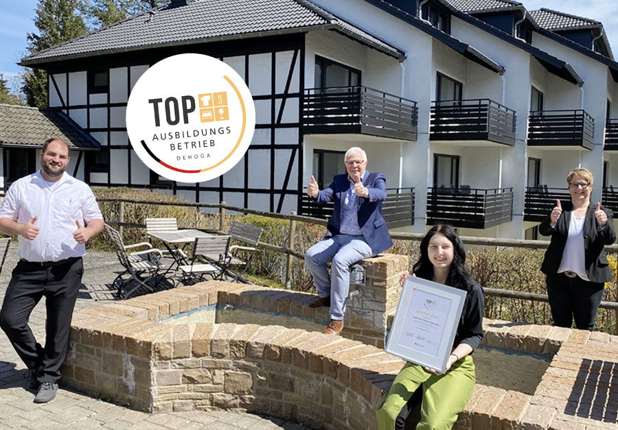 Hoteldirektor und Mitarbeiter des Sporthotel Grafenwald stehen vor dem Apartmenthaus und freuen sich über die Auszeichnung als Top Ausbildungsbetrieb