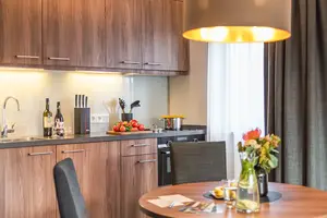 Blick über einen kleinen, runden Küchentisch hinweg auf die dahinterliegende Küche.