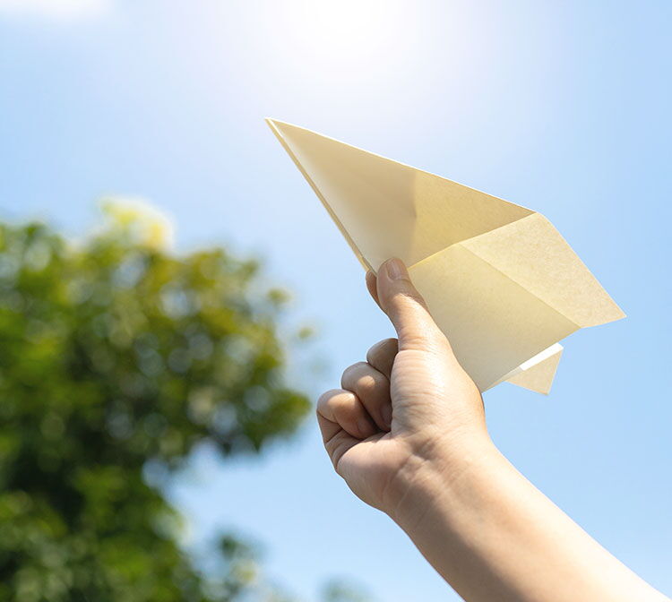 Eine Person hält einen Papierflieger in die Luft um ihn los fliegen zu lassen