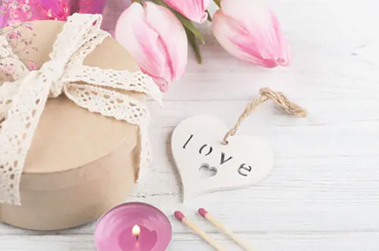 Blumen, Kerze und ein Schild mit Love für die Candle Light Massage im Grafenwald