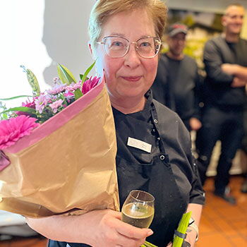 Natalie Maurer hält einen großen Blumenstrauß und ein Glas Wein in den Händen