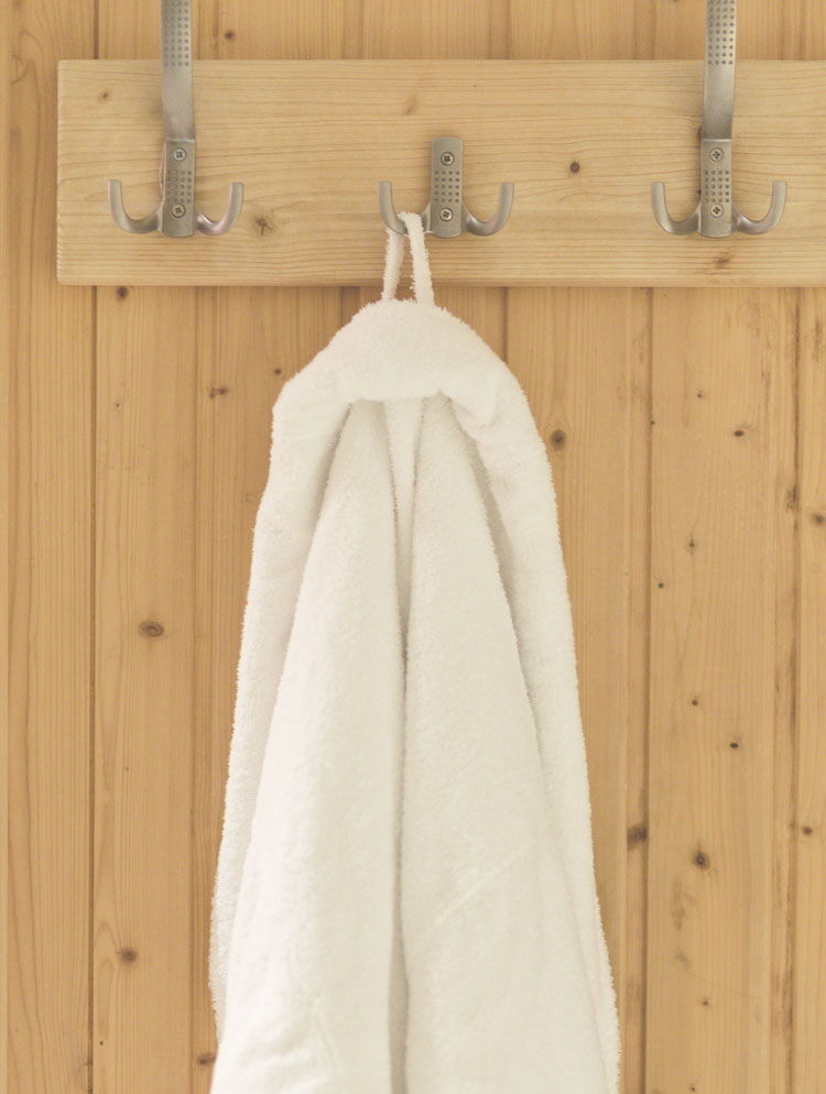 Im Sauna Bereich des Sporthotel Grafenwald hängt ein Bademantel an einem Haken an der Saunawand