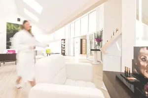 Eine Frau im Bademantel, die durch die helle Eingangshallte der Beauty geht
