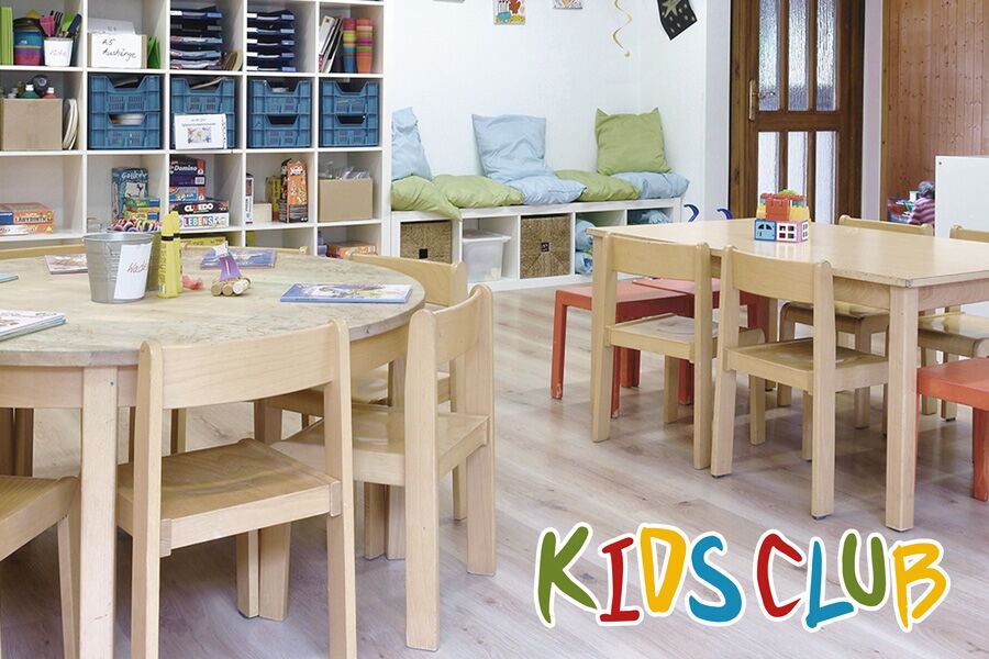 Blick in den Kids Club mit Kindertischen und -stühlen, Regalen und dem Kids Club Logo