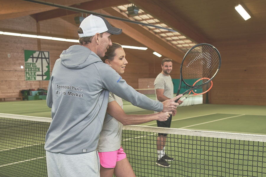 Tennistrainer Marcus Merkel zeigt Tennisschülerin den richtigen Abschlag
