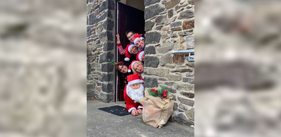 Mitarbeiter des Senionrentreffs sind als Nikoläuse verkleidet und schauen um die Ecke